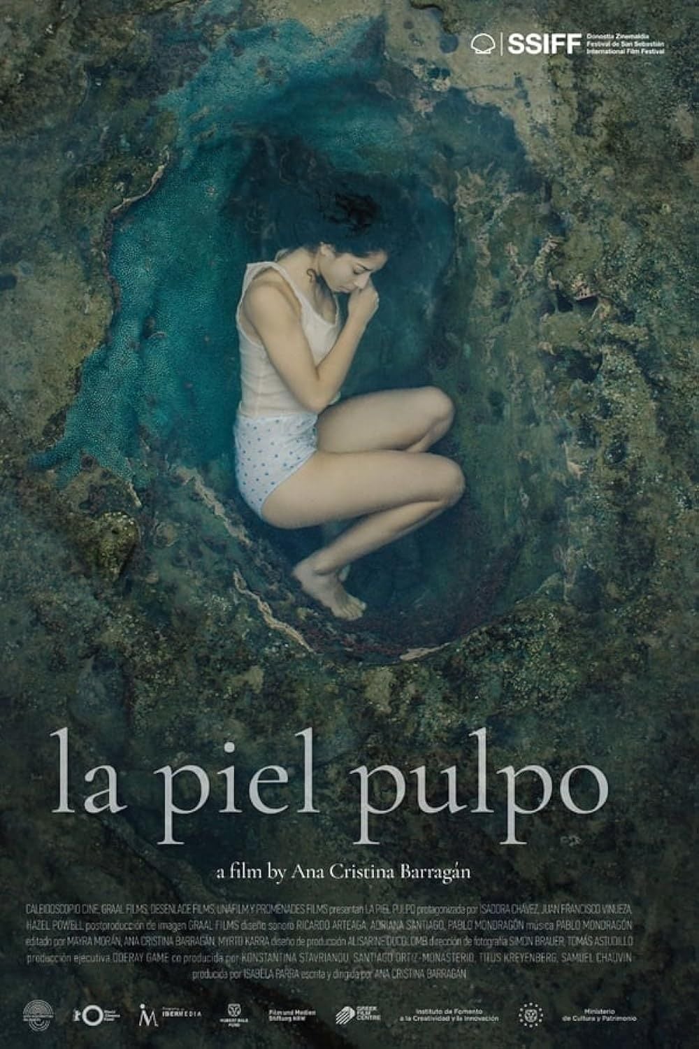 Cartel de la película 'La piel pulpo' con los actores Paulet Arévalo e Isadora Chávez en un entorno de isla rocosa, dirigida por Ana Cristina Barragán.